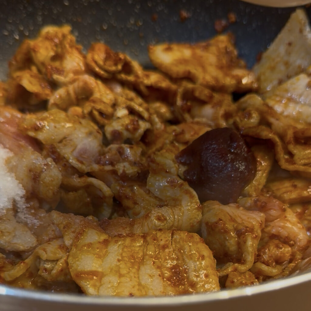 Pork cooking with gochujang in a pan