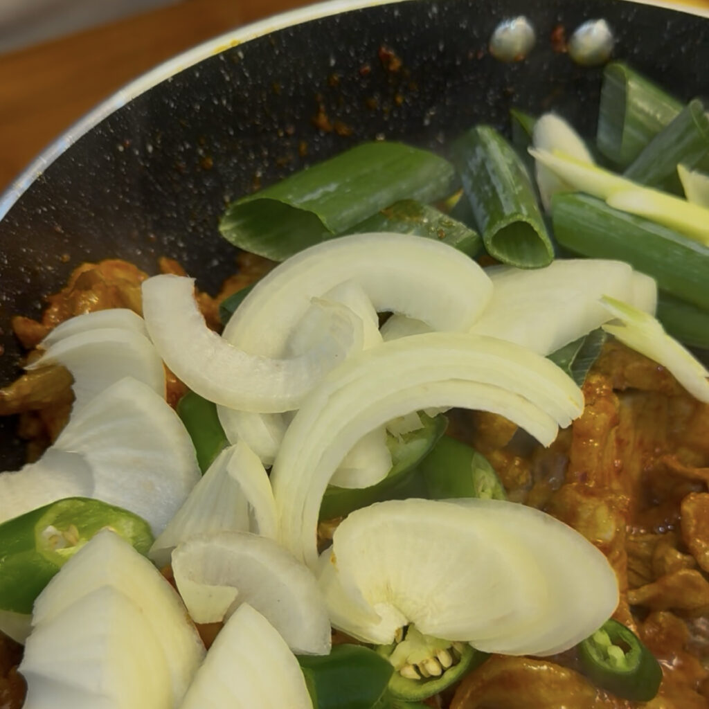 Adding onions and green onions to Korean spicy pork