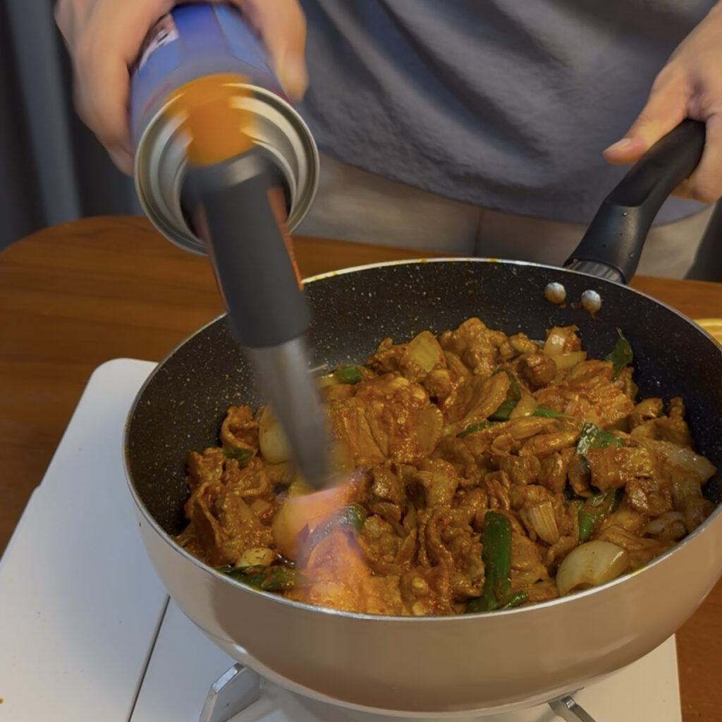 Using a butane torch to add smoky flavor to Jeyuk Bokkeum