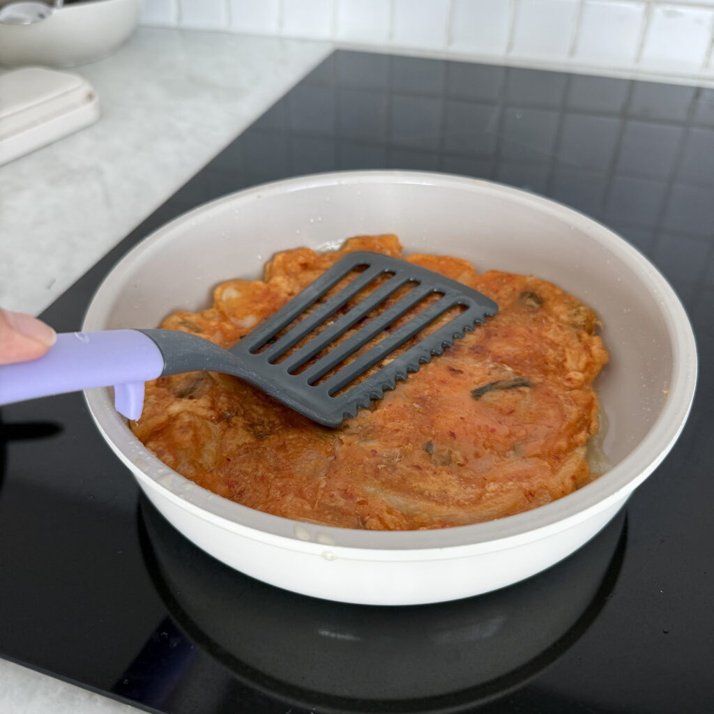 Flipping a kimchi pancake until golden brown and crispy