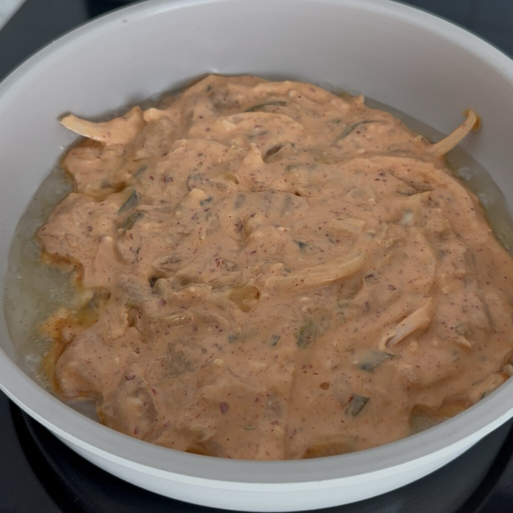Spreading kimchi pancake batter in a hot frying pan