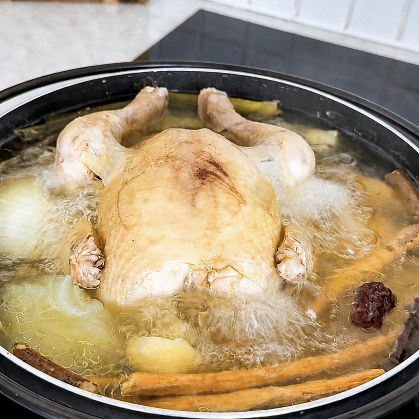 A bowl of homemade Korean Samgyetang made with a whole chicken, garlic, and herbs, served as a traditional summer comfort food.