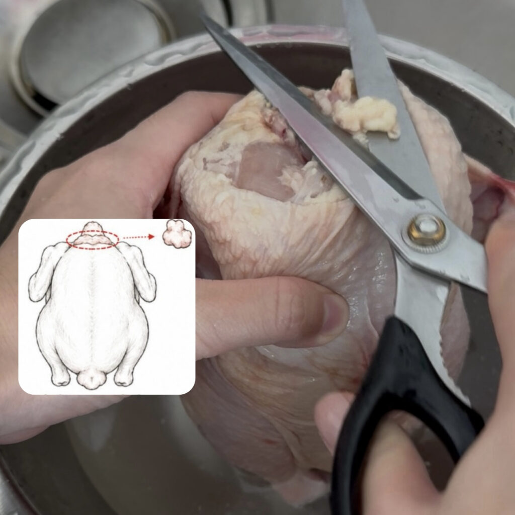 Removing excess fat from the neck of a whole chicken before cooking.