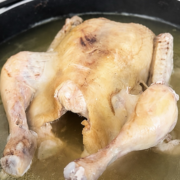 Samgyetang simmering in a pot to create a rich, flavorful broth.