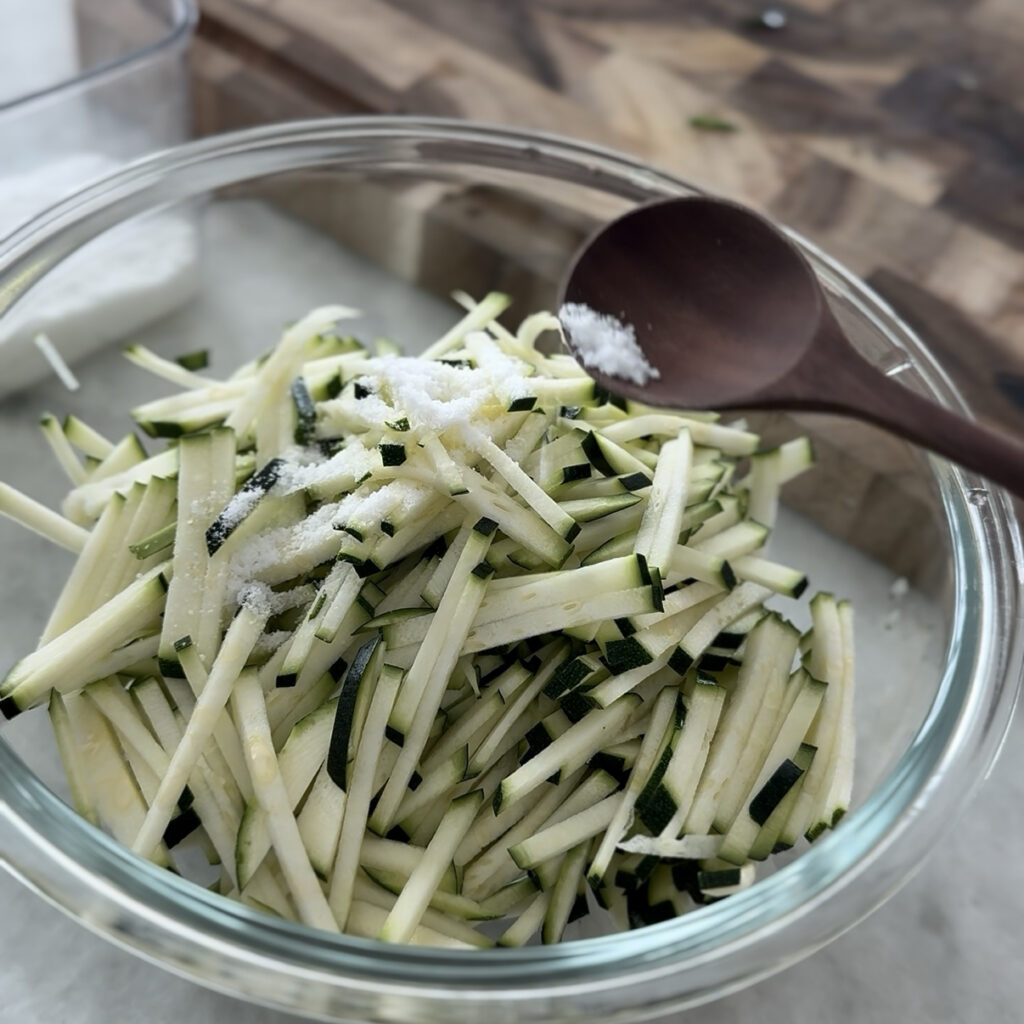Julienned zucchini mixed with salt and resting in a bowl before making Korean zucchini pancake (Hobak Jeon).