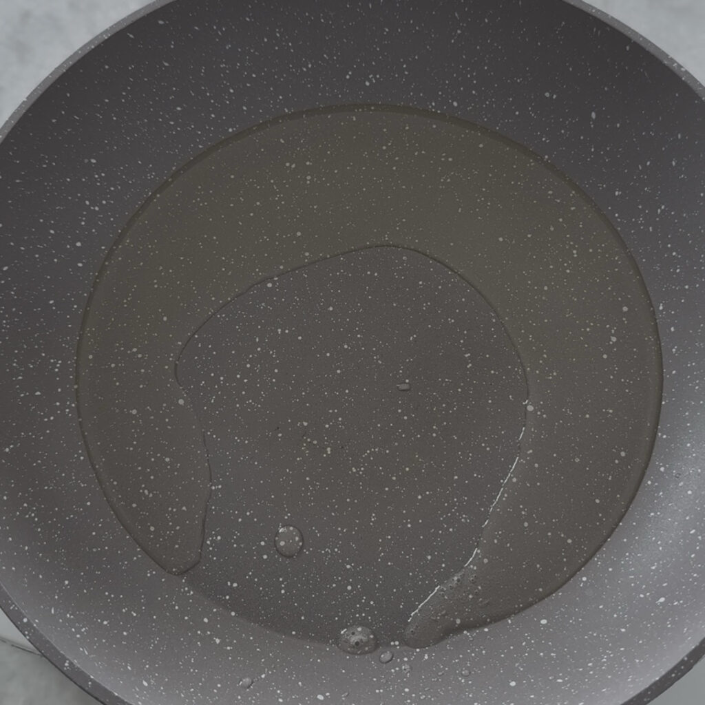 Adding vegetable oil to a hot skillet before cooking Korean zucchini pancake.