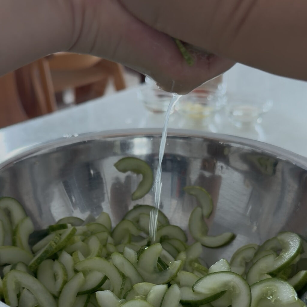 Squeezing excess water from salted cucumbers