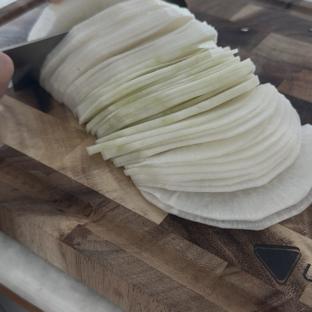 Thinly slicing daikon radish for homemade Korean pickled radish.