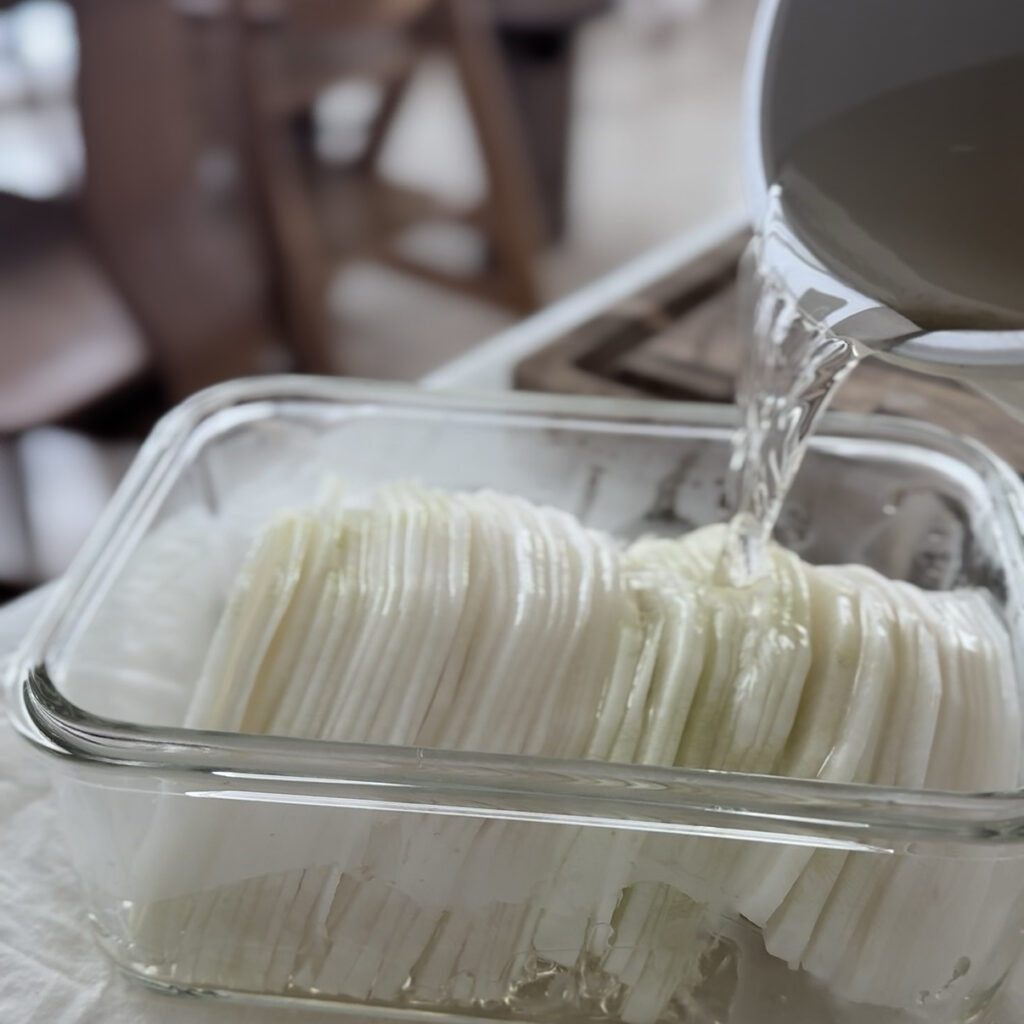 Adding white vinegar to the hot pickling liquid.
