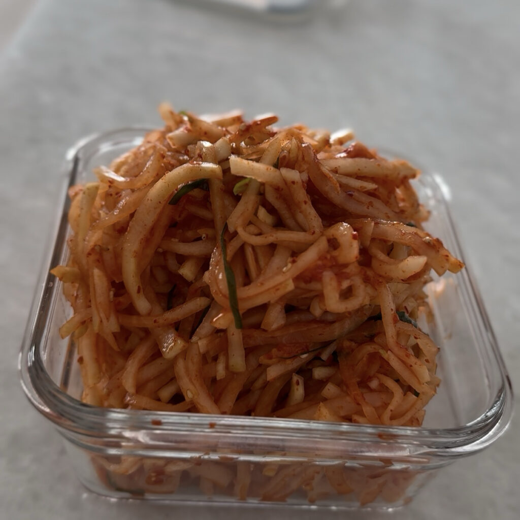 Fresh homemade Korean spicy radish salad in a storage container.