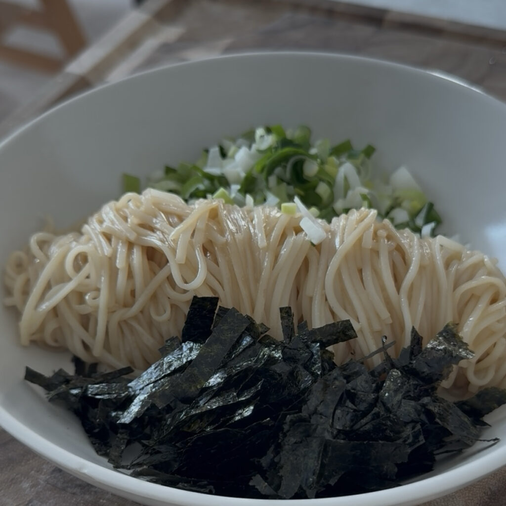 Roasted seaweed, and sliced green onion being added to the noodles.