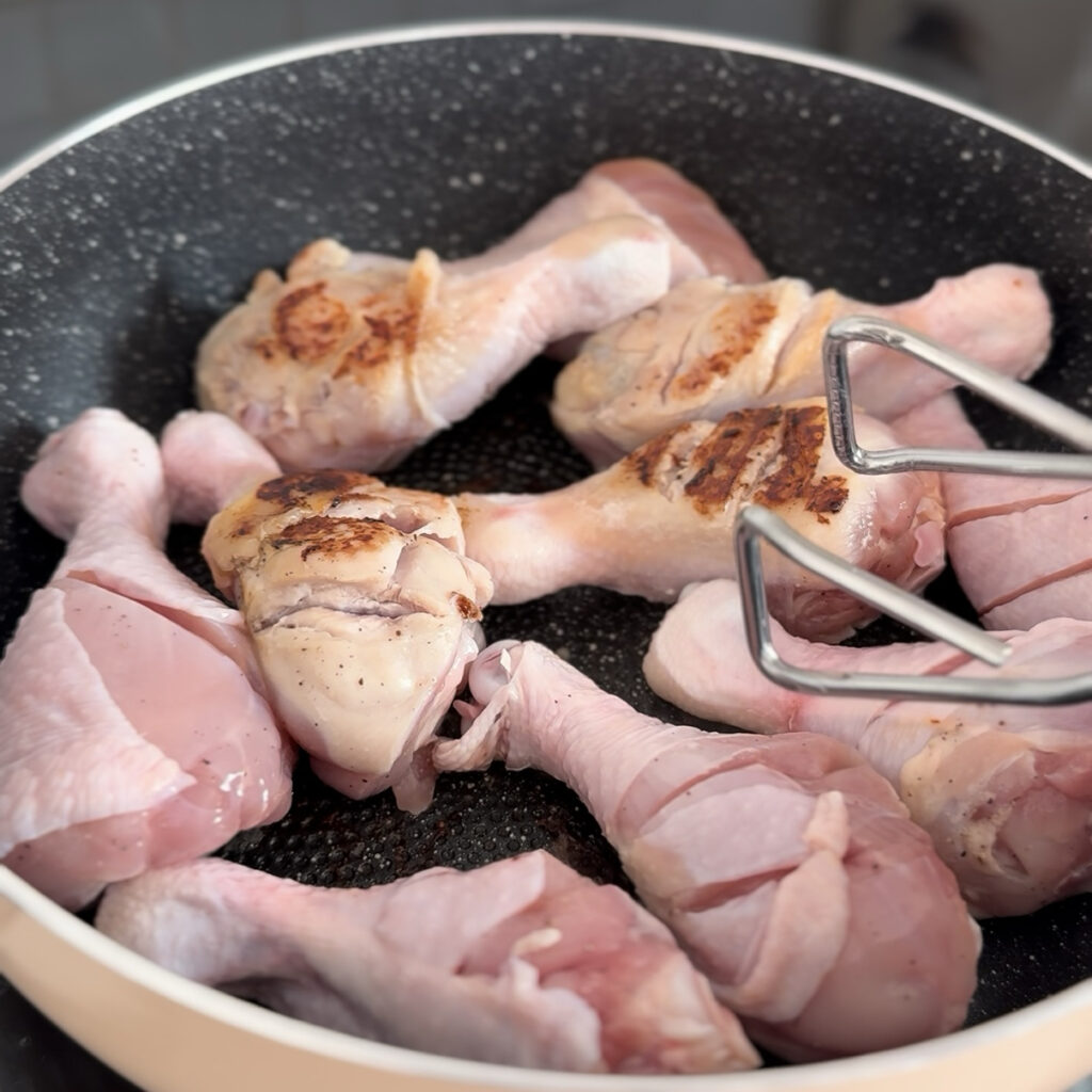 Browning chicken drumsticks in a pan