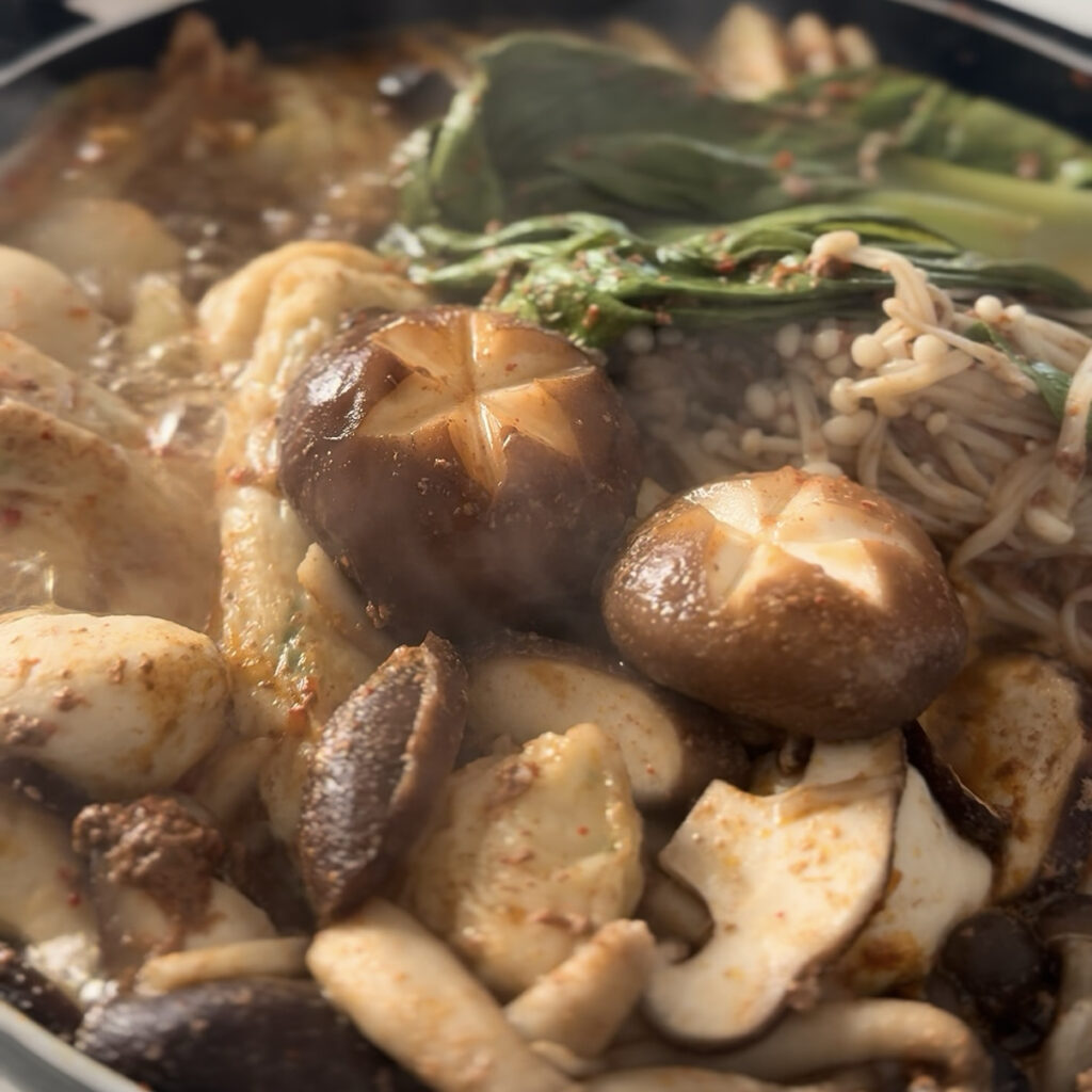 Easy homemade Korean spicy shabu shabu served with beef, mushrooms, and fresh vegetables.