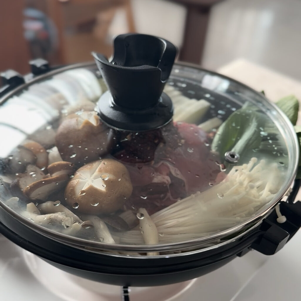 Covering the pot before simmering the Korean spicy shabu shabu.