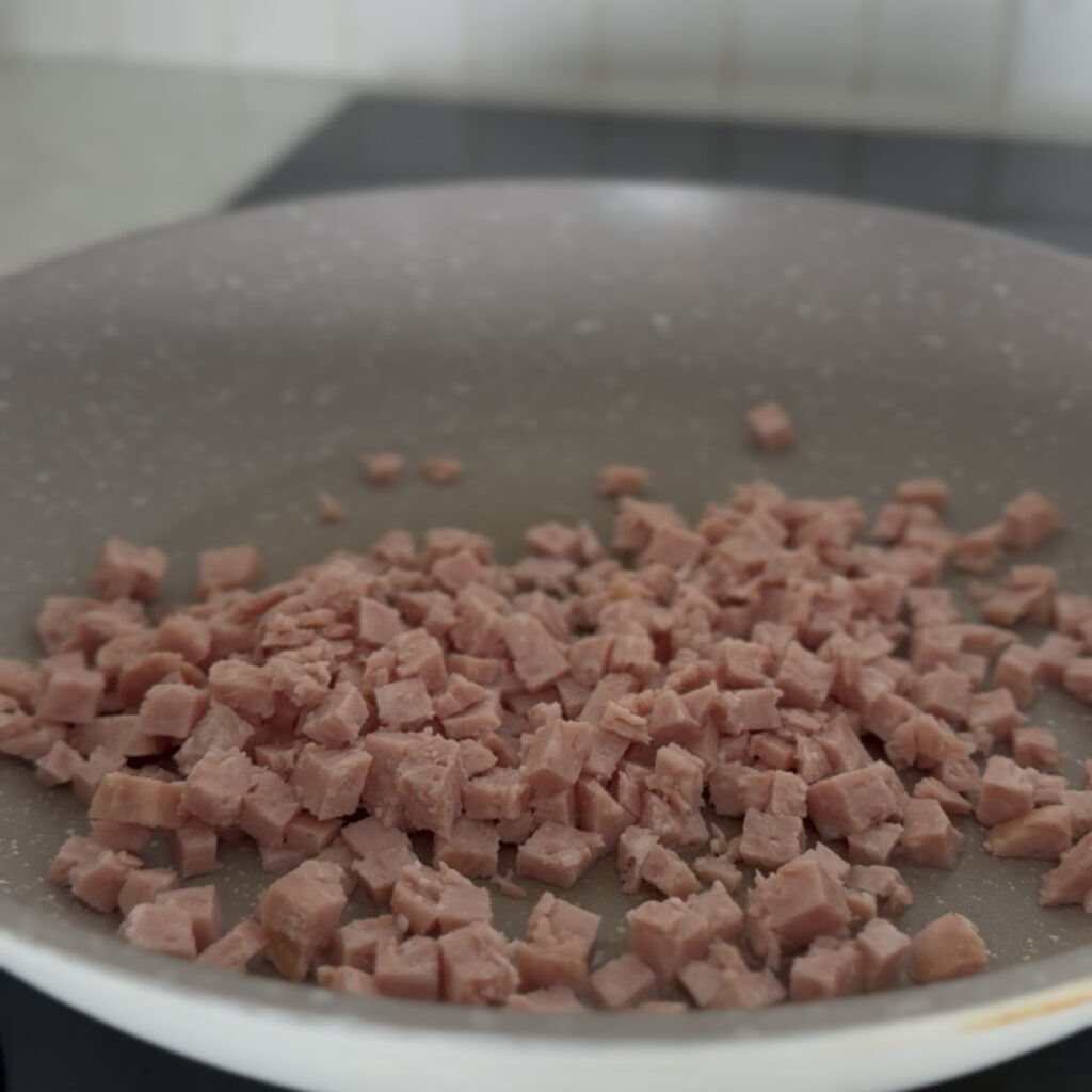 Diced Spam cooking in a skillet until lightly golden