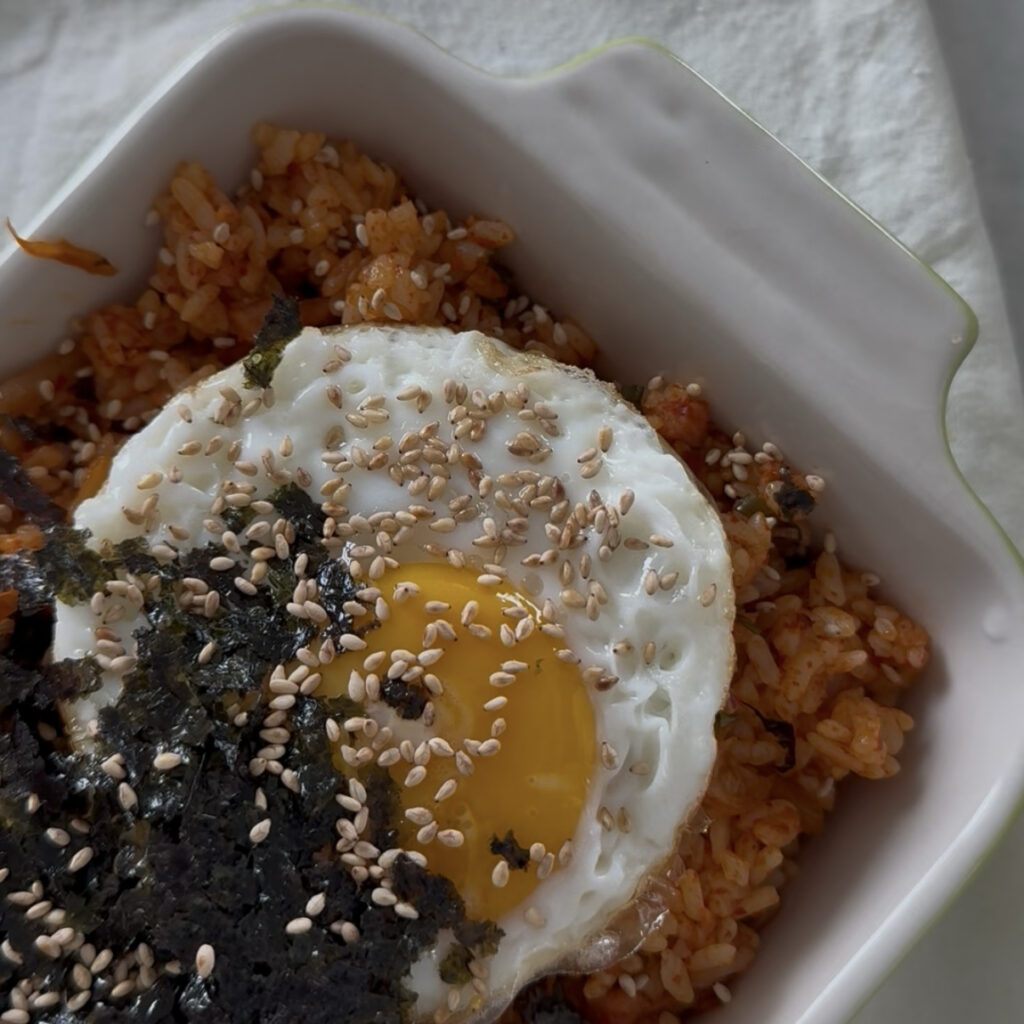 Spam kimchi fried rice topped with a fried egg, seaweed, and sesame seeds