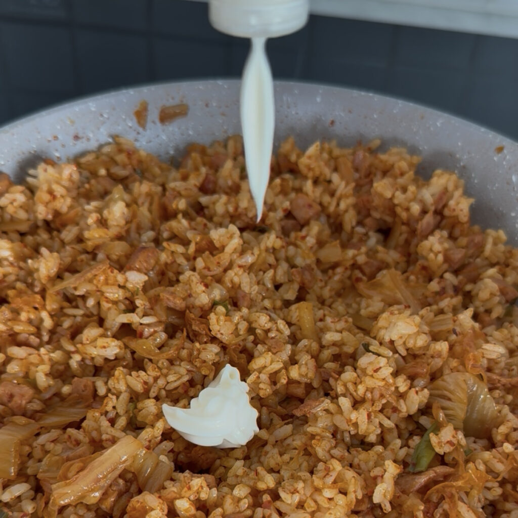 Mayonnaise being mixed into hot Spam kimchi fried rice
