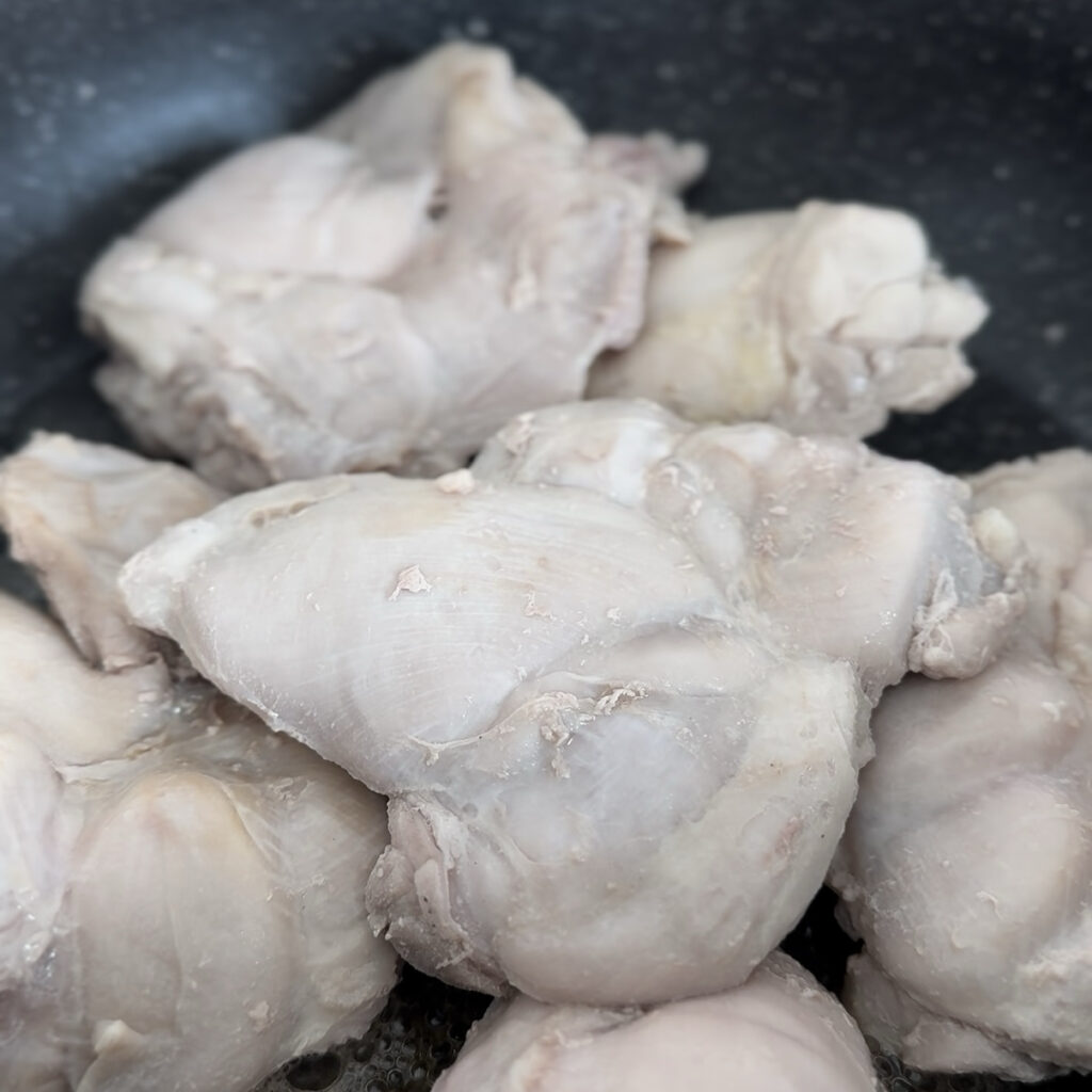 Chicken thighs cooking in sesame oil before adding the sauce.