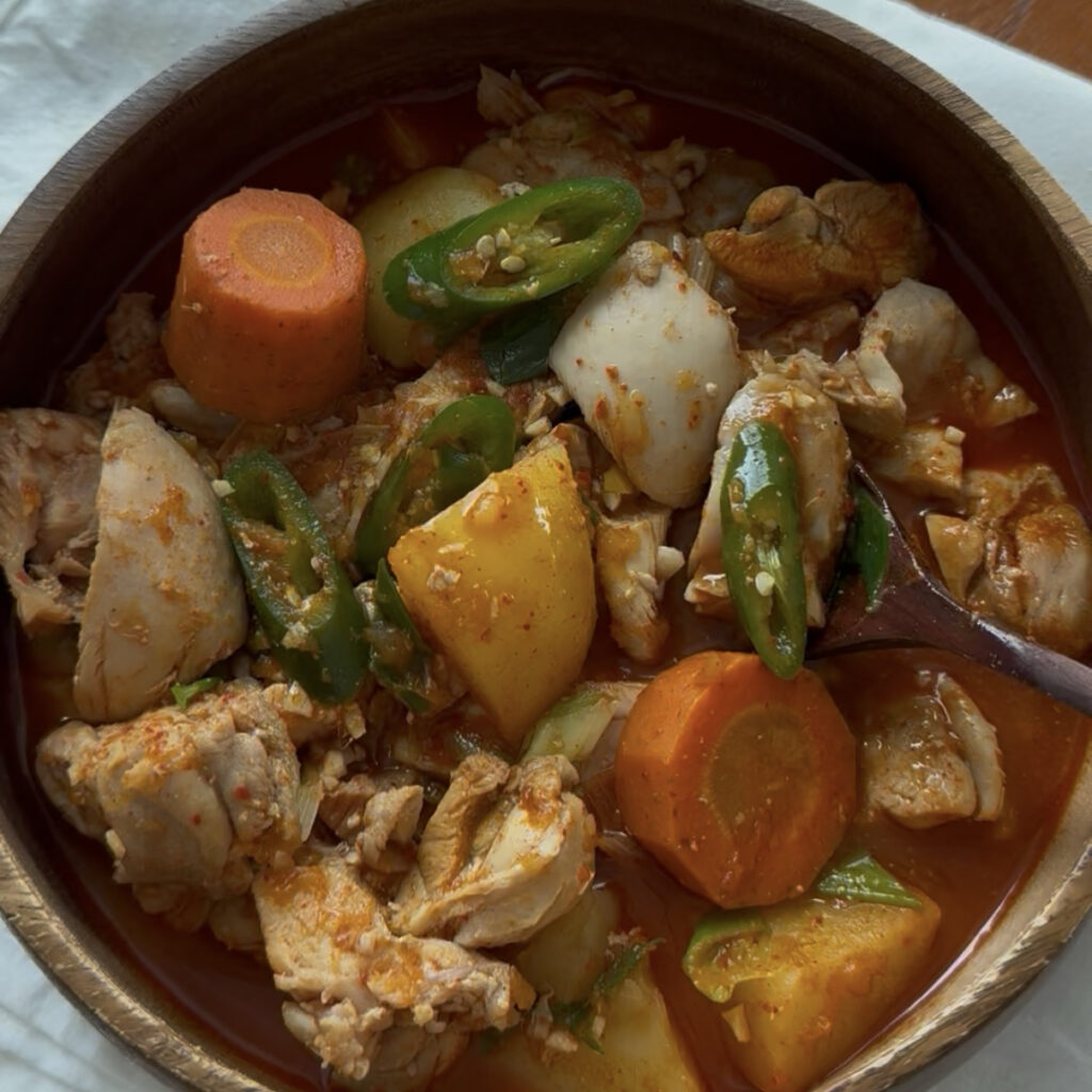 Korean spicy chicken stew with tender chicken, potatoes, carrots, and green chili in a rich red sauce.