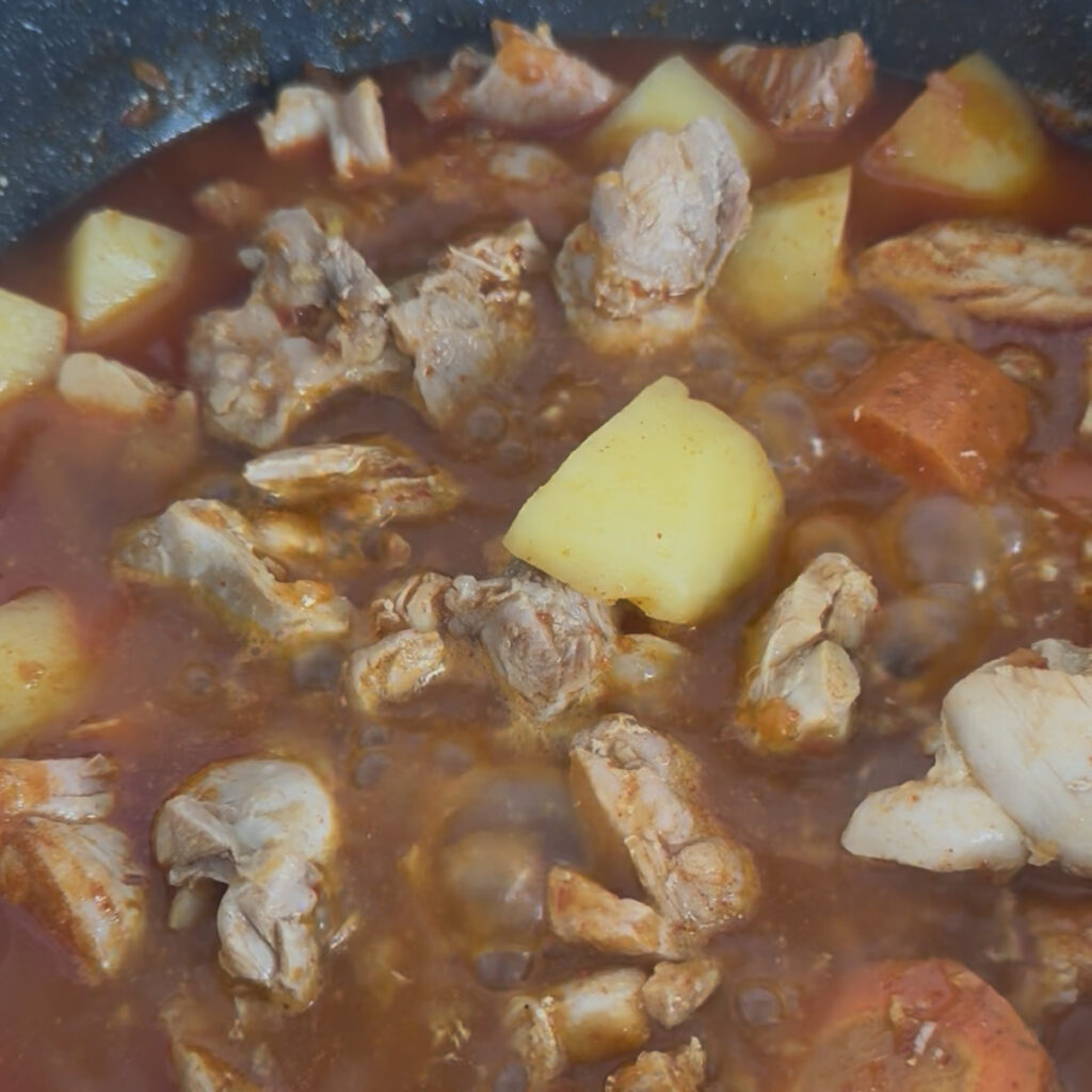 Chicken and vegetables simmering in a rich Korean spicy sauce.