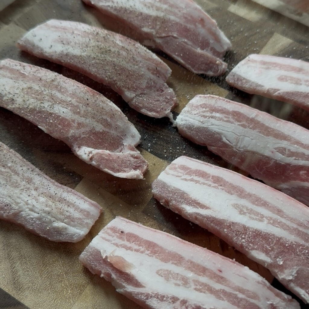 Seasoning sliced pork belly with salt and black pepper