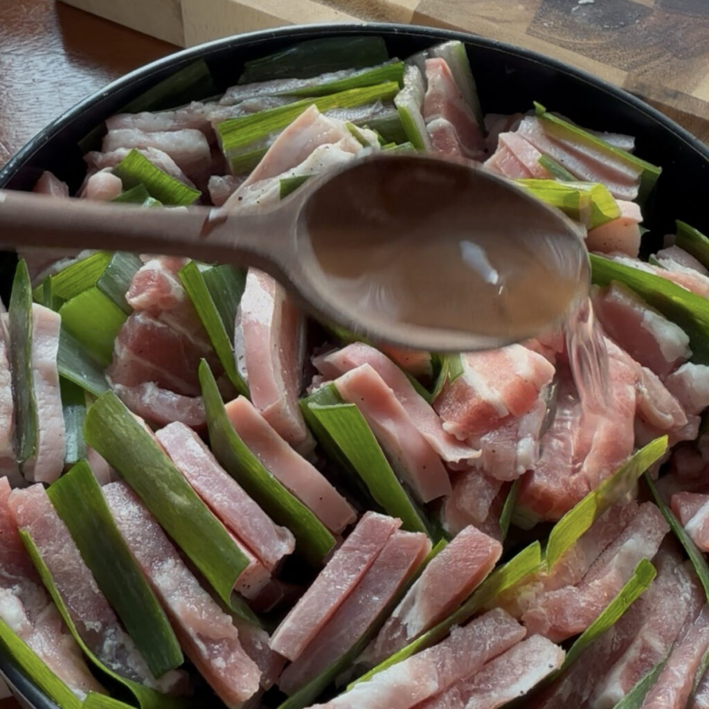 Pouring mirin over the pork before cooking