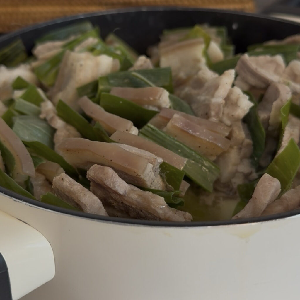 Close-up of tender Korean pork belly with cooked green onions
