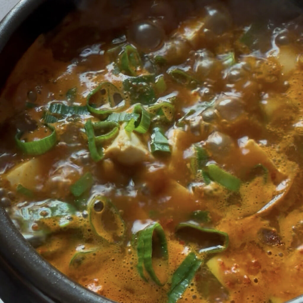Adding sliced green onion to Korean doenjang jjigae