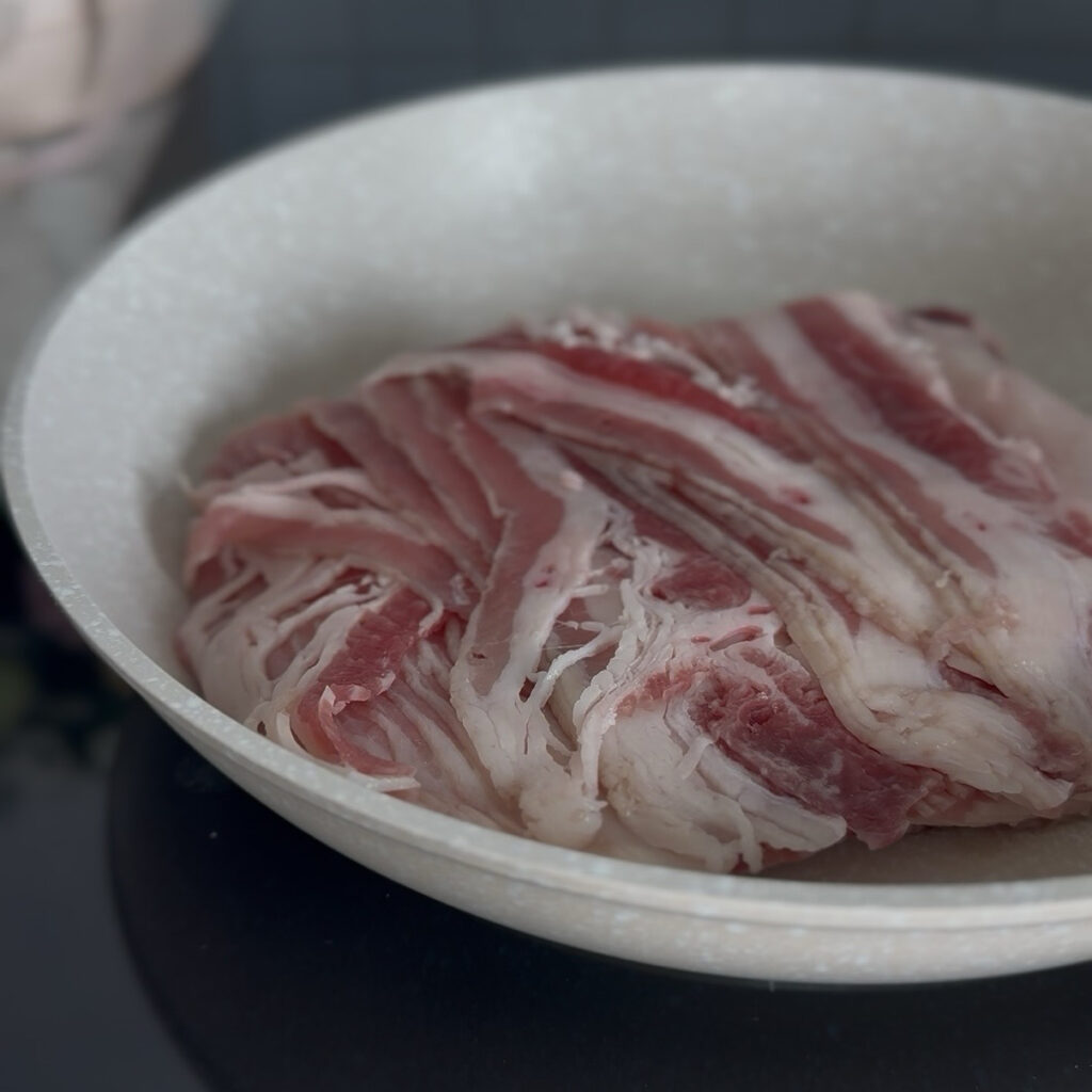 Thinly sliced beef belly cooking in a skillet