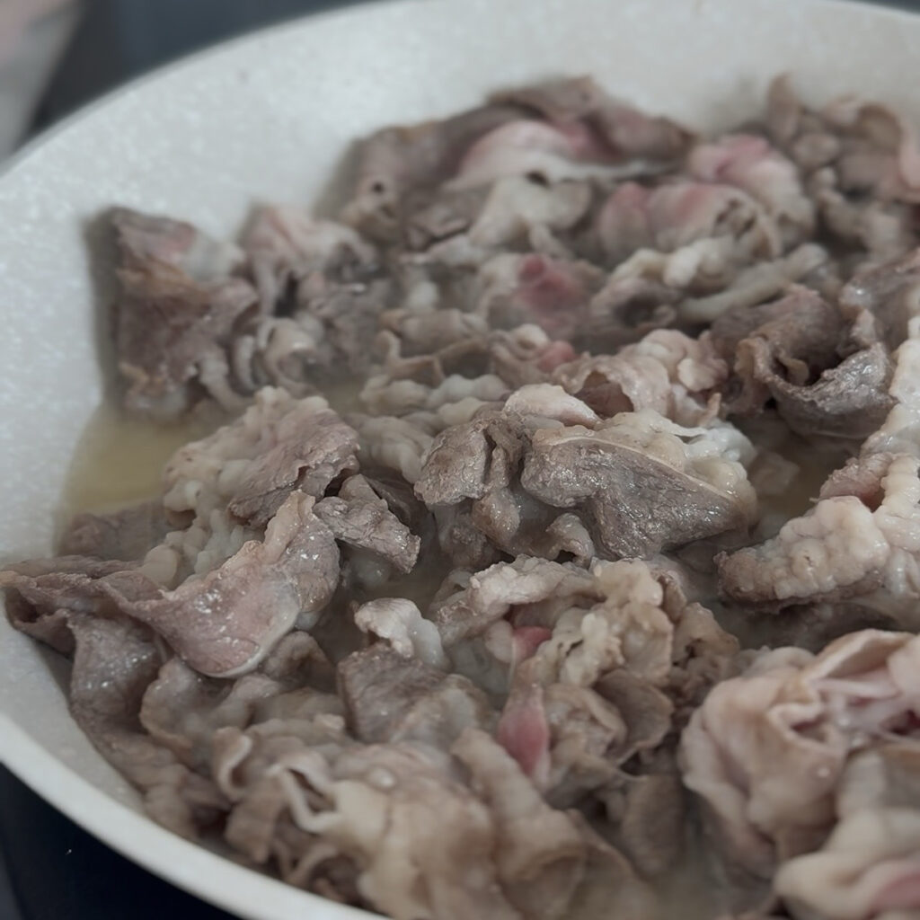 Thinly sliced beef belly releasing fat as it cooks