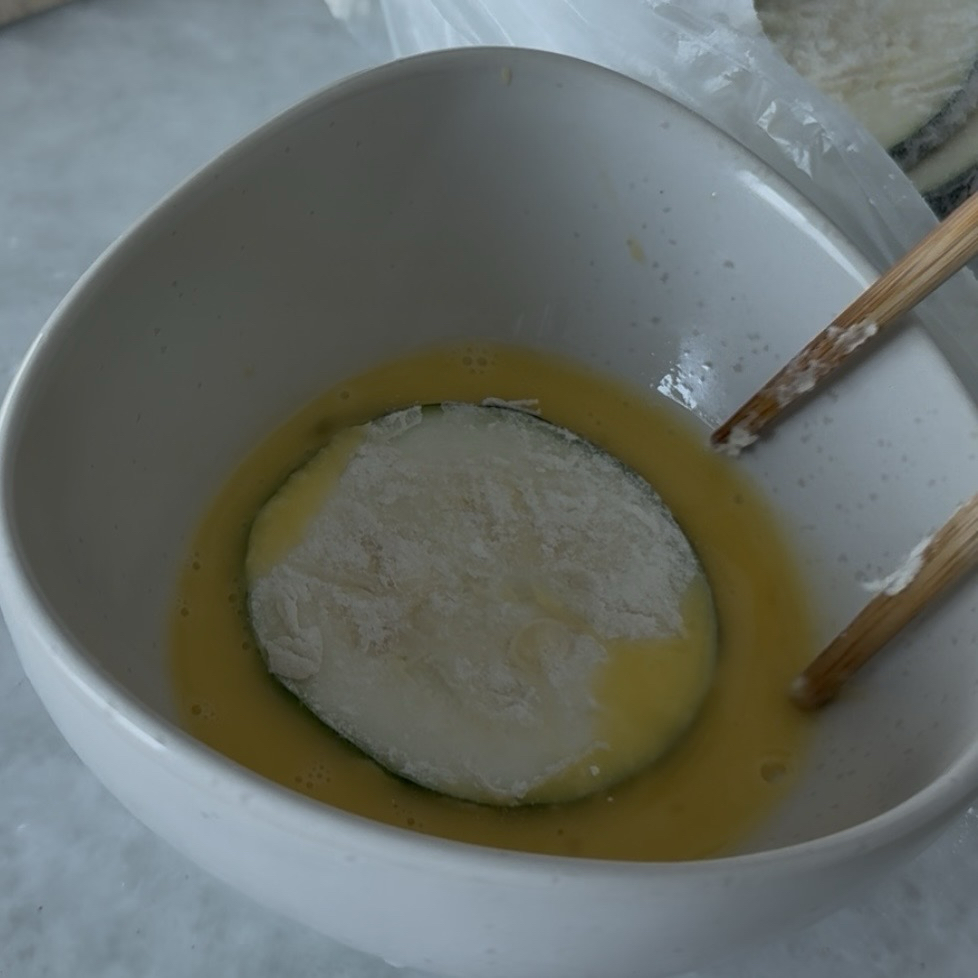 Dipping flour-coated zucchini slices into beaten egg